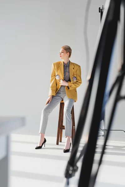 Enfoque selectivo de modelo elegante posando y sentado en el taburete en el backstage — Stock Photo