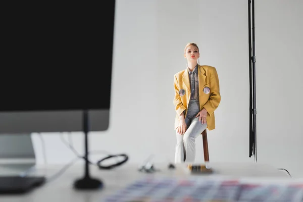 Foco seletivo de modelo elegante posando e sentado nas fezes nos bastidores — Fotografia de Stock