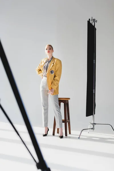 Foyer sélectif de modèle élégant posant avec la main sur la hanche sur les coulisses — Photo de stock