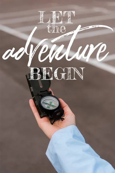 Cropped view of woman holding compass near let the adventure begin letters — Stock Photo