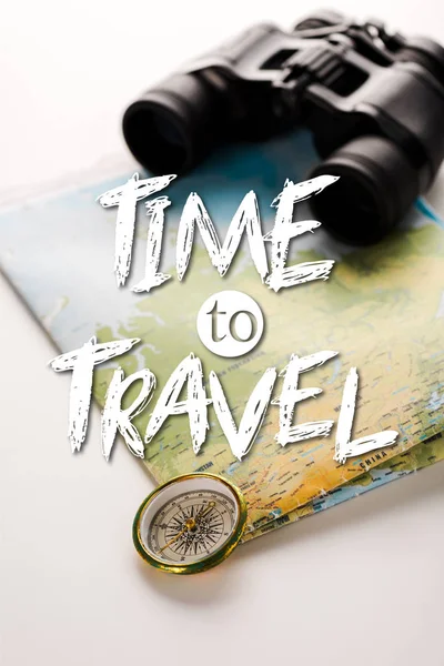 Brújula dorada cerca del mapa, binoculares y tiempo para viajar letras en blanco - foto de stock