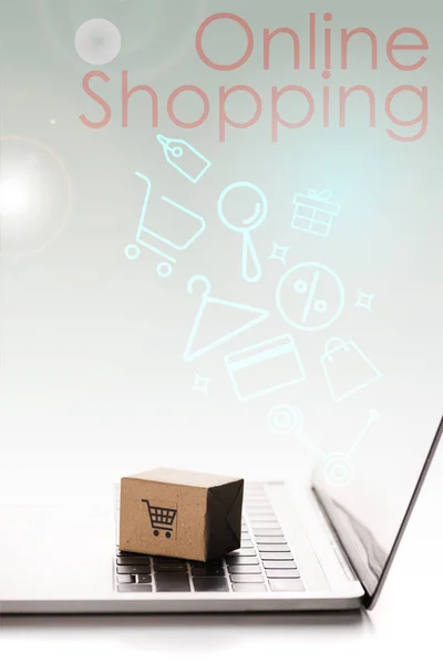 Caja de juguetes en el teclado del ordenador portátil cerca de la ilustración y las cartas de compras en línea en blanco, concepto de comercio electrónico - foto de stock