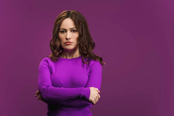 Mujer disgustada de pie con brazos cruzados sobre fondo púrpura — Stock Photo