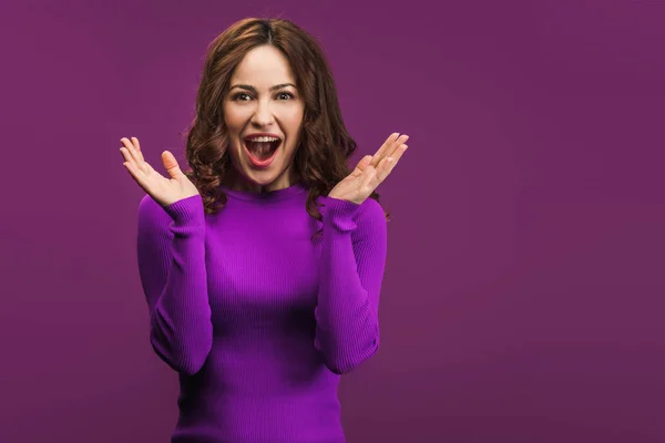 Suprised woman standing with open arms on purple background — Stock Photo