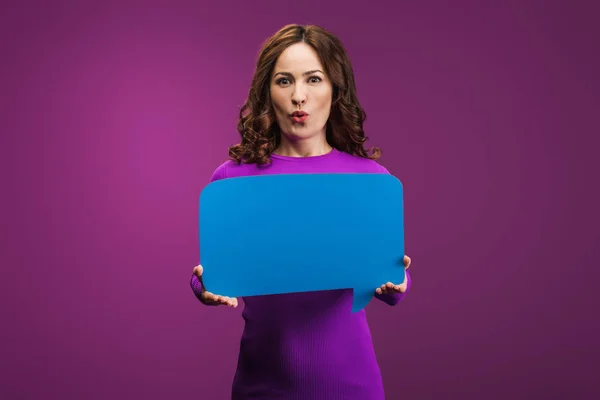Surprised woman holding speech bubble on purple background — Stock Photo