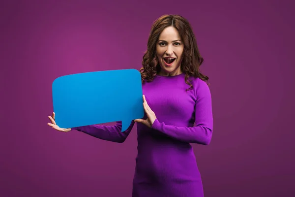 Excited woman holding speech bubble on purple background — Stock Photo