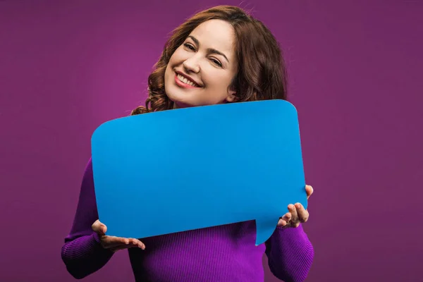 Happy woman holding speech bubble on purple background — Stock Photo