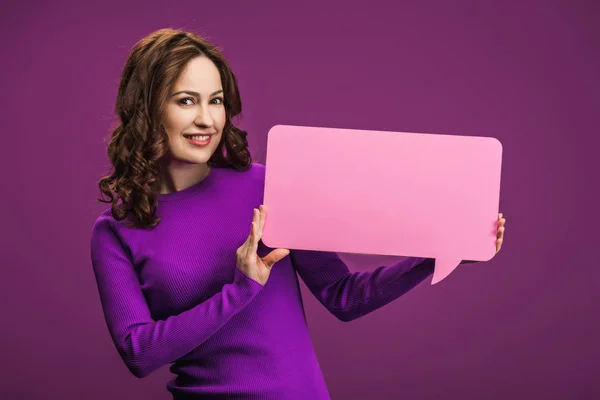 Smiling woman holding speech bubble on purple background — Stock Photo