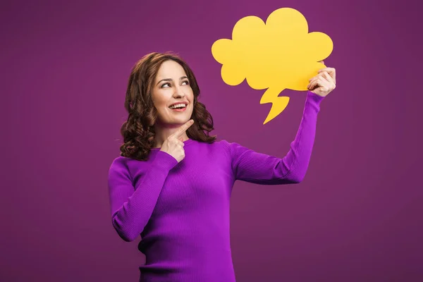 Lächelnde Frau zeigt mit dem Finger auf Gedankenblase auf lila Hintergrund — Stockfoto
