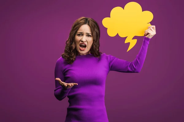 Irritated woman screaming while holding thought bubble on purple background — Stock Photo