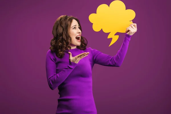 Angry woman screaming while holding thought bubble on purple background — Stock Photo