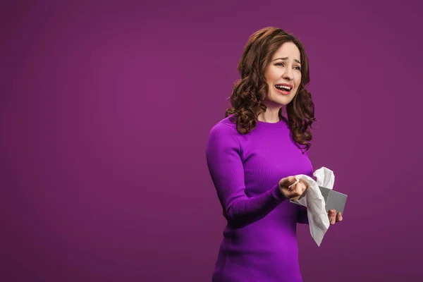 Crying woman looking away while holding paper napkins on purple background — Stock Photo