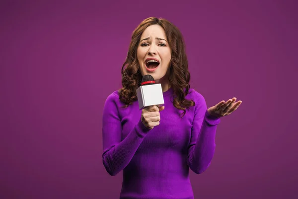 Сердитий репортер кричить на мікрофоні на фіолетовому фоні — стокове фото