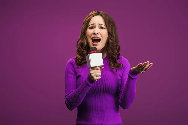 Angry reporter screaming in microphone on purple background — Stock Photo