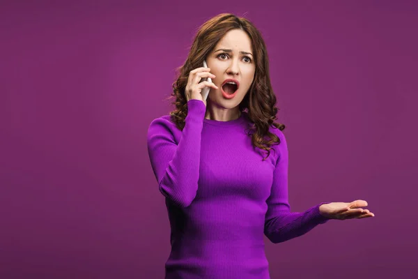 Сердита жінка кричить під час розмови на смартфоні на фіолетовому фоні — стокове фото