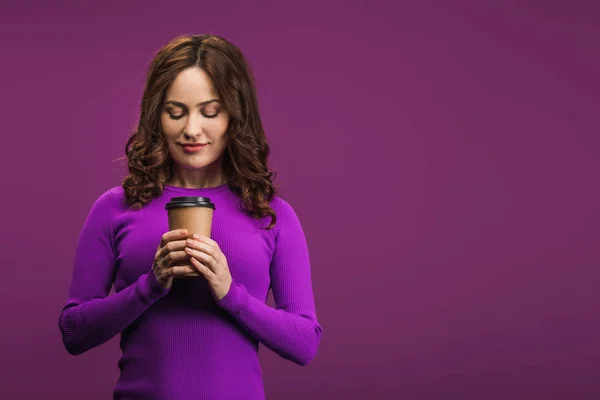 Sonriente chica sosteniendo café para ir en púrpura fondo - foto de stock