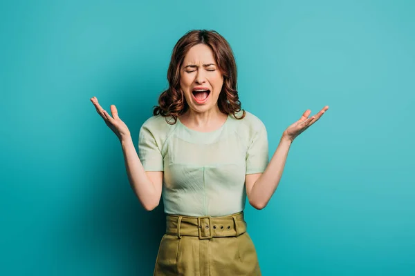 Angry woman screaming with closed eyes on blue background — Stock Photo