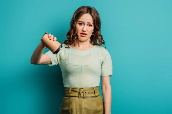 Bouleversé femme regardant caméra tout en secouant tasse en papier vide sur fond bleu — Photo de stock