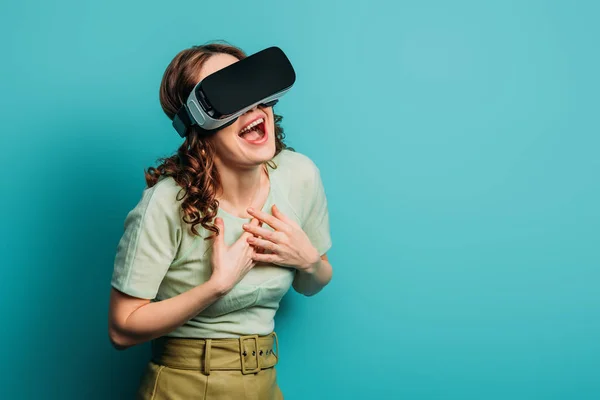 Cheerful girl in vr headset laughing on blue background — Stock Photo