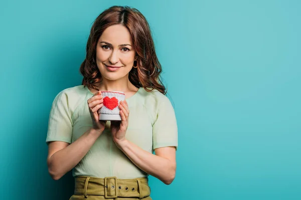 Happy girl holding cup with heart symbol on blue background — Stock Photo