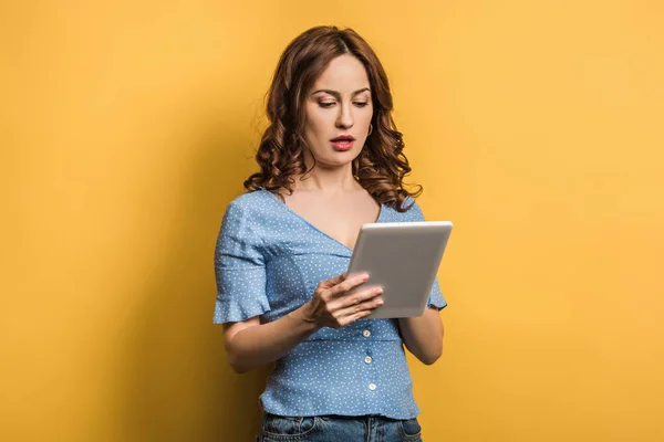 Mulher atenta usando tablet digital no fundo amarelo — Fotografia de Stock