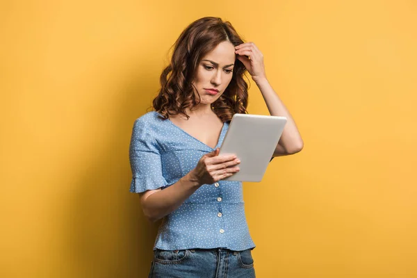 Mulher pensativa tocando cabeça ao usar tablet digital no fundo amarelo — Fotografia de Stock