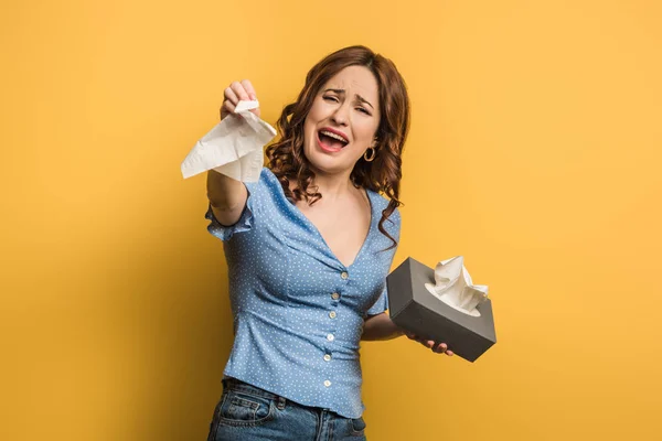 Menina chateada chorando ao mostrar guardanapo de papel no fundo amarelo — Fotografia de Stock