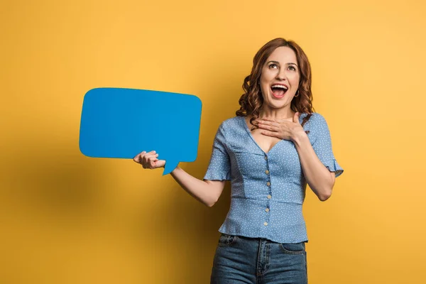 Chica emocionada riendo mientras sostiene la burbuja del habla sobre fondo amarillo - foto de stock