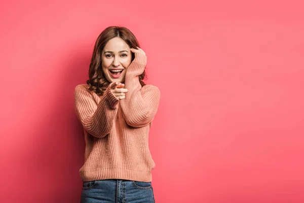 Ragazza allegra che punta con il dito alla macchina fotografica su sfondo rosa — Foto stock