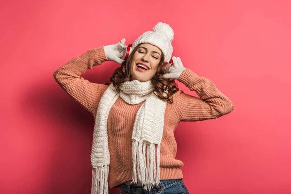 Chica feliz cantando en auriculares inalámbricos con los ojos cerrados sobre fondo rosa - foto de stock