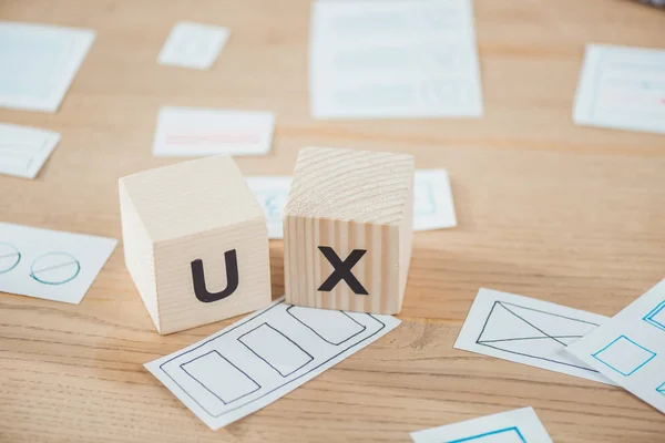 Selective focus of wooden cubes with ux letter and layouts on table — Stock Photo