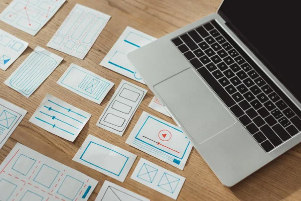 Vue grand angle des croquis de développement d'applications ux et de l'ordinateur portable sur une table en bois — Photo de stock