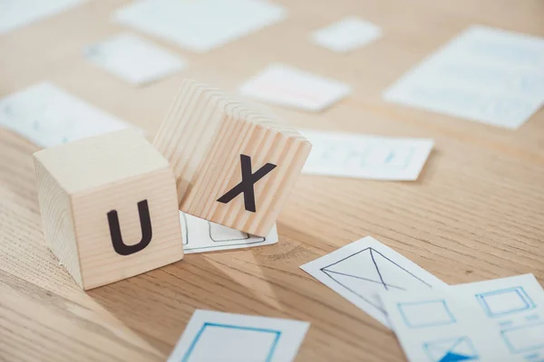 Selective focus of wooden cubes with ux letters and application layouts on table — Stock Photo