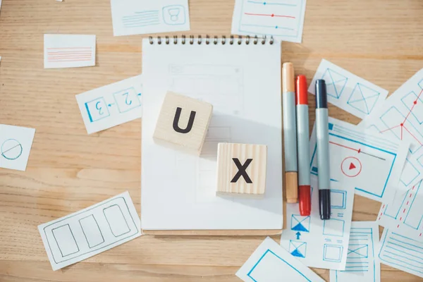 Vista superior de cubos com letras ux e esboços de desenvolvimento de aplicativos do site ux na mesa de madeira — Fotografia de Stock