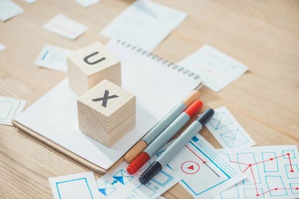 Selective focus of letters ux on cubes with website app development sketches on wooden table — Stock Photo