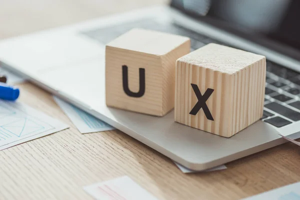 Selektive Fokussierung der UX-Buchstaben auf Würfel am Laptop mit Webskizzen auf dem Tisch — Stockfoto