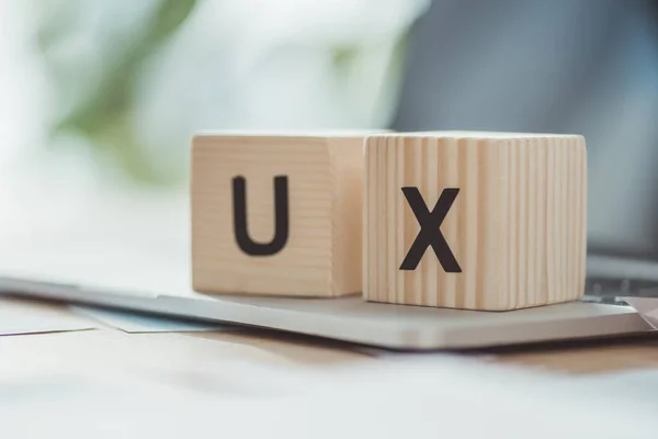 Selektive Fokussierung von Holzwürfeln mit UX-Buchstaben auf Laptop auf Tisch — Stockfoto