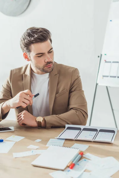 Designer regardant des croquis de wireframe de site Web avec des modèles ux sur la table — Photo de stock