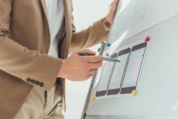 Cropped view of designer making notes on app interface sketches on whiteboard in office — Stock Photo