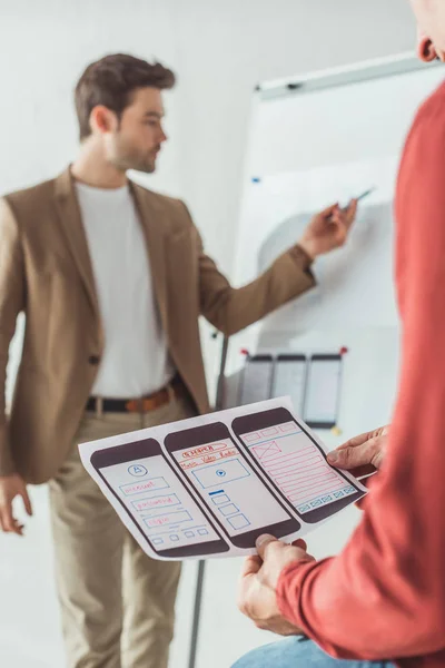 Selektiver Fokus des kreativen Designers mit mobilen Website-Skizzen, während Kollege Whiteboard im Büro — Stockfoto