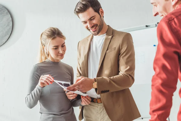 Foco seletivo de designers sorridentes trabalhando com aplicativos móveis se estende no escritório — Fotografia de Stock