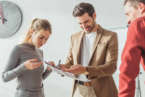 Smiling designers noticing on wireframe sketches of mobile website in office — Stock Photo