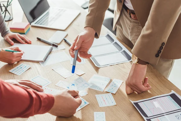 Vista ritagliata di progettisti che sviluppano user experience design con schizzi sul tavolo — Foto stock