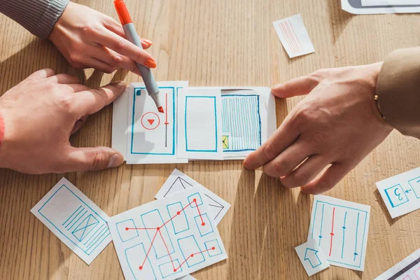 Cropped view of creative designers developing user experience design with layouts on table — Stock Photo