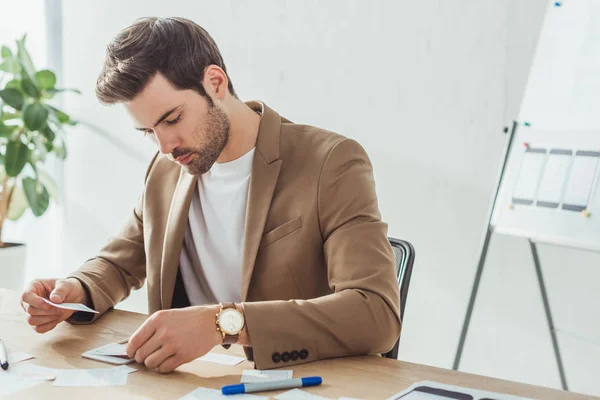 Bonito designer criativo desenvolvendo design de experiência do usuário com esboços na mesa — Fotografia de Stock