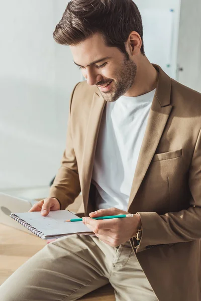 Smiling ux designer avec ordinateur portable esquisse la conception de l'expérience utilisateur dans le bureau — Photo de stock