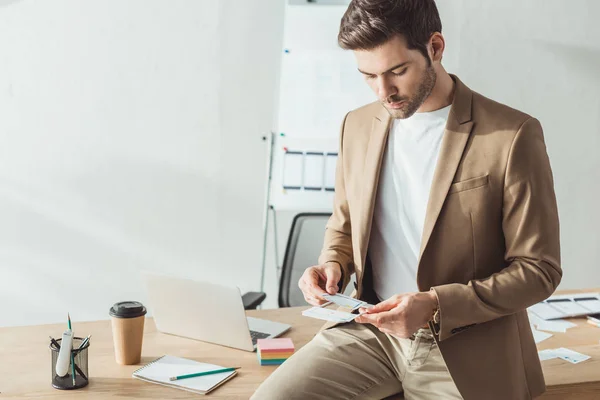 Handsome designer developing mobile website design with layouts by office table — Stock Photo