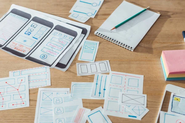 Selective focus of mobile website sketches and layouts on wooden table — Stock Photo