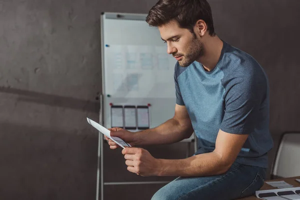 Side view of ux designer holding sketches while sitting at table in office — Stock Photo