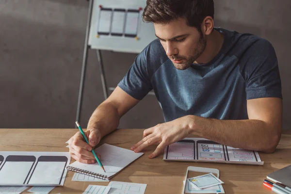 Focalisation sélective des croquis créatifs ux designer avec modèle web mobile sur la table — Photo de stock